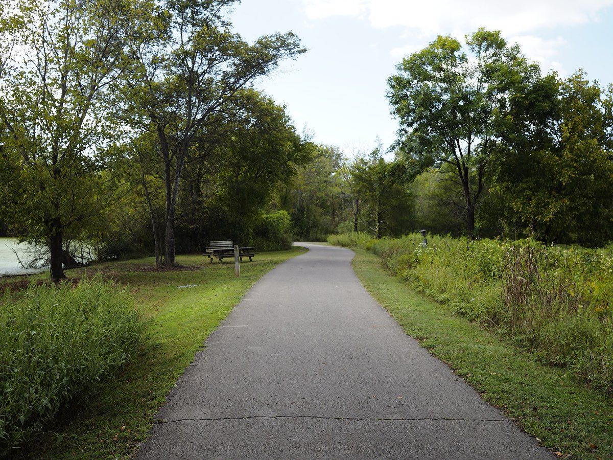 A paved greenway path winding past trees and open water at Shelby Bottoms in Nashville.